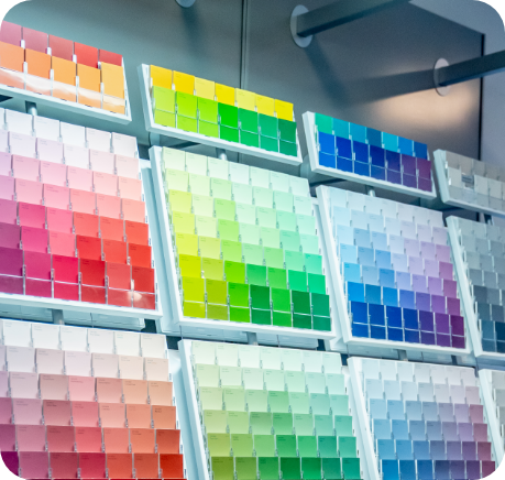 A display of multiple paint color swatch palettes arranged in rows and columns, showcasing a variety of hues ranging from reds and pinks on the left to greens, yellows, blues, and purples on the right. The well-lit setup emphasizes the vibrant colors, ideal for exterior or interior commercial painting services.